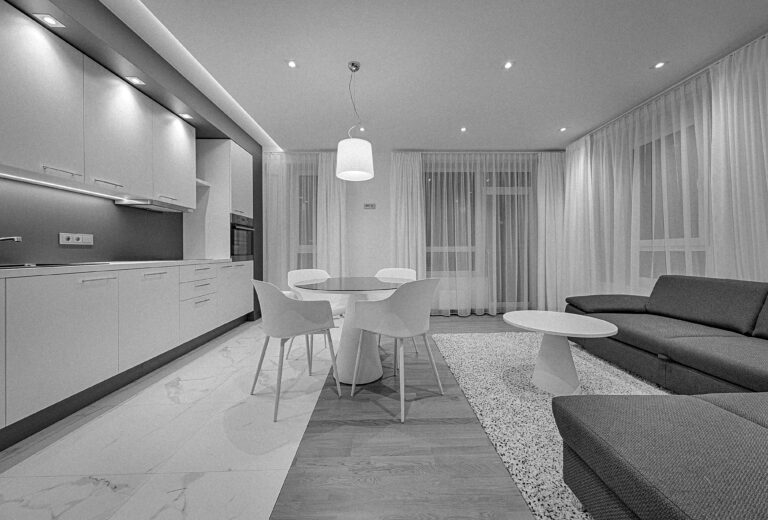 Spacious, well-lit living space featuring a dining table, sofa, and kitchen area.